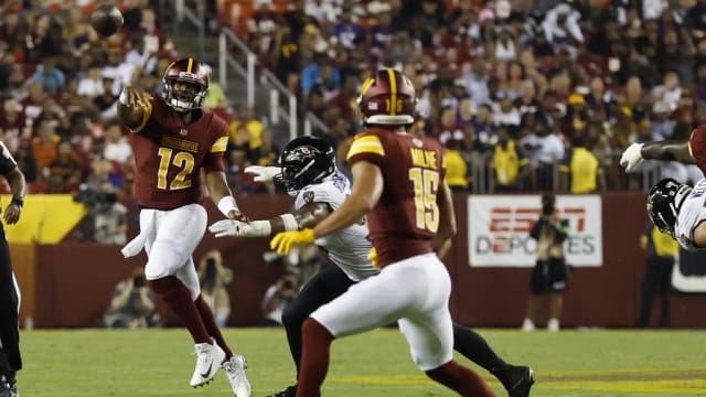 Washington Commanders quarterback Jacoby Brissett (12) passes the ball to Commanders wide receiver Dax Milne (15) as Baltimore Ravens linebacker Tavius Robinson (95) chases during the third quarter at FedExField.